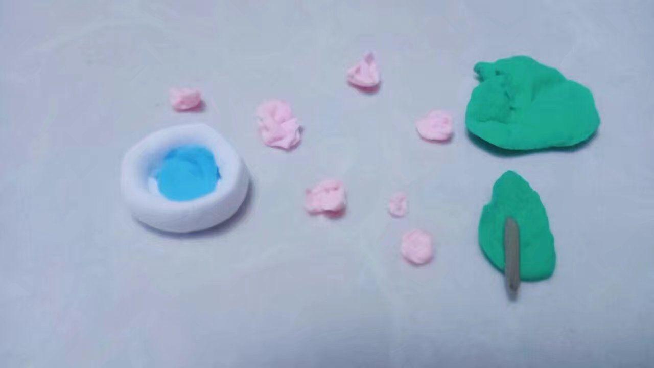 第一步:可根据自己喜好捏出装饰的花、树叶 第二步:粘到3楼做的垫子上 原图第一步:捏出几朵樱花(我弄的不像)用牙签或其他工具做出花瓣线条(可选多种层次的粉色,用丙烯做出渐变色效果更佳) 原图第二步:用深褐色的粘土捏成长条做树枝(深褐色=黑色+红色)再用绿色粘土捏出扁平的类似三角形的图案做树叶,将树叶粘到树枝上,再用牙签挤压出树叶纹路 原图第三步:用白色(其他颜色也行)粘土捏出小碟子,一点点就行不用太多,再用蓝色或深褐色捏成水或酱油粘在碟子里 原图第四步:把以上捏好的装饰粘在3楼的垫子上 温馨提示:做小